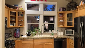 A kitchen with wooden cabinets, a stainless steel refrigerator, a sink, and a window with a view of the outside. - NW Crossing Getaway with all the amenities (Bend)