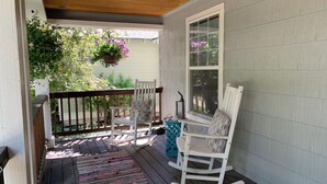 A porch with two rocking chairs, a colorful rug, and a hanging flower basket. - NW Crossing Getaway with all the amenities (Bend)