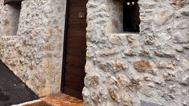 A stone building with a wooden door and a small window with lights. - LA CASA DI NORIS (Fiuggi)