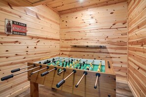 A foosball table in a room with wooden walls and a Coca-Cola sign. - Twin Creeks | Hocking Hills (Logan)