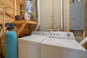 A laundry room with two washing machines, a water heater, and a water tank.
