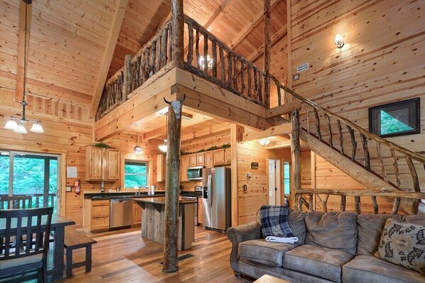 A spacious cabin with a loft bedroom, a kitchen, and a living area with a sofa and a dining table.