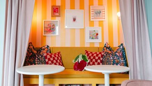 A room with a striped wall, a sofa with patterned cushions, and a small table.