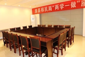 A conference room with a long table and chairs, a red banner with white text, and a whiteboard on the wall.