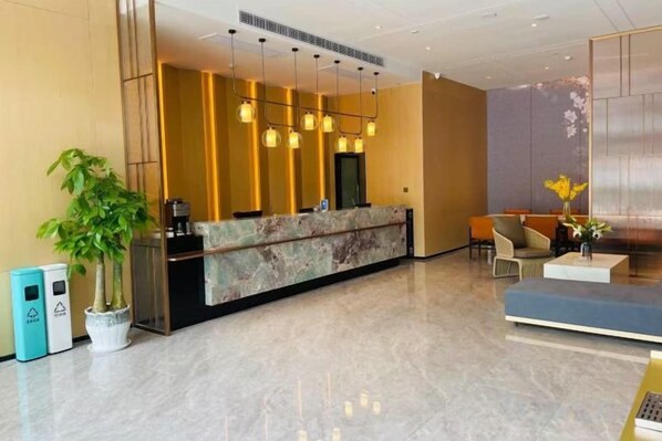 A hotel reception area with a marble counter, seating, and a large plant.