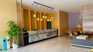 A modern reception area with a marble counter, pendant lighting, a seating area with a sofa, and a potted plant. - Yongle Star Hotel (Shiyan Fang County) (Fang County)