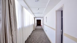 A long, narrow hotel corridor with a carpeted floor, white walls, and a door on the right. - Yongle Star Hotel (Shiyan Fang County) (Fang County)