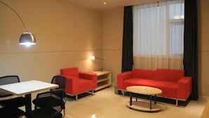 A modern room with a dining table, two red sofas, a round coffee table, and a large window with sheer curtains. - Yongle Star Hotel (Shiyan Fang County) (Fang County)
