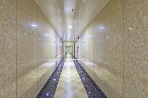 A long, narrow hallway with marble walls and a patterned floor, leading to a door at the end. - Guangzhou Business Hotel (Shangxiajiu Pedestrian Street Changshou Road Subway Station Branch) (Guangzhou)