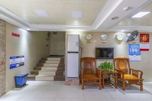 A reception area with a staircase, a television, and wooden chairs.