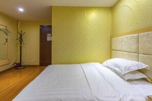 Une chambre d’hôtel avec un lit, un porte-manteau et une porte.