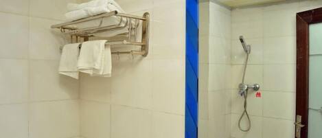 A bathroom with a shower, a towel rack with towels, and a door with a handle.