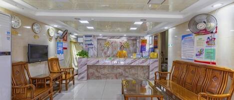 A reception area with a marble counter, wooden furniture, a television, and informational posters.