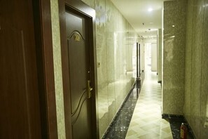 A hallway with a wooden door, marble walls, and a checkered floor. - Guangzhou Business Hotel (Shangxiajiu Pedestrian Street Changshou Road Subway Station Branch) (Guangzhou)