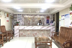 A reception desk with a marble top, wooden chairs, a wooden table, and a clock on the wall. - Guangzhou Business Hotel (Shangxiajiu Pedestrian Street Changshou Road Subway Station Branch) (Guangzhou)