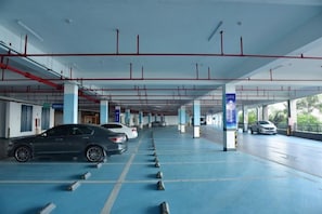 Een parkeergarage met meerdere verdiepingen, betonnen pilaren en geparkeerde auto's.