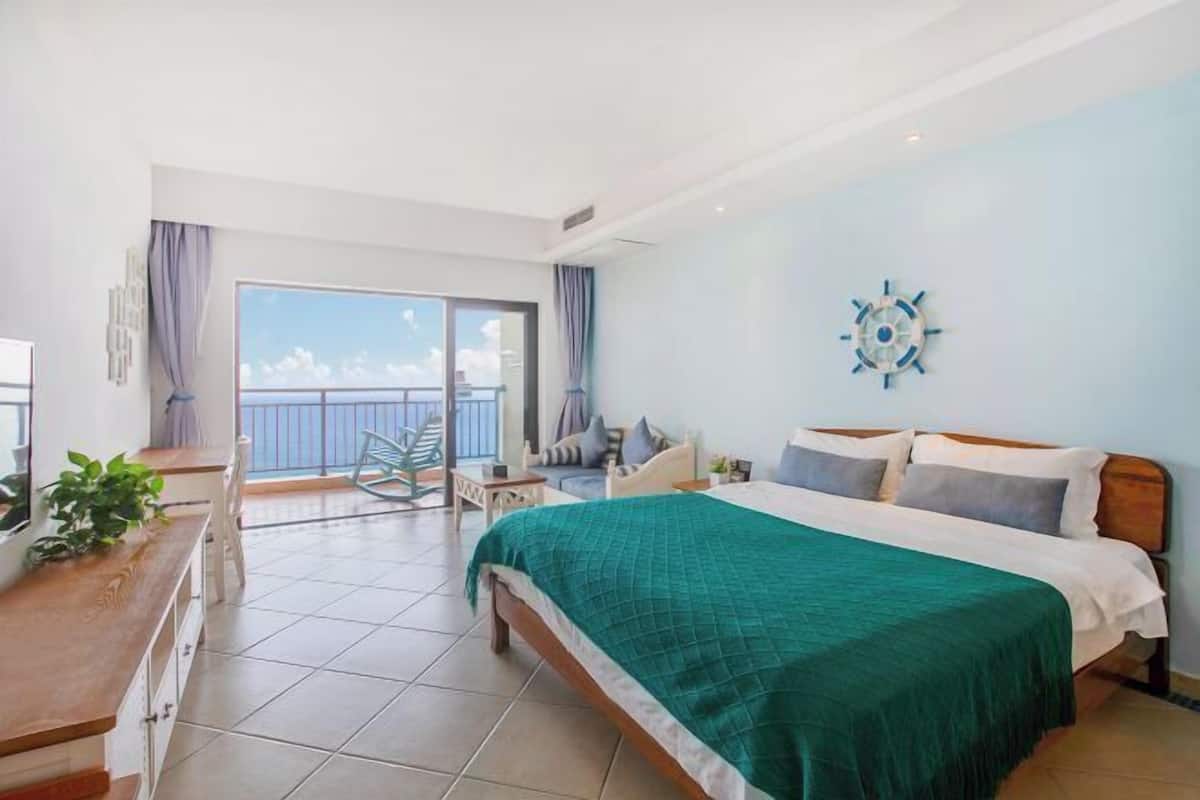 Une chambre avec un lit, un bureau, une chaise, un balcon avec vue et un élément décoratif mural.