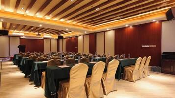 Un salón de conferencias con filas de mesas y sillas, un atril y un escenario.