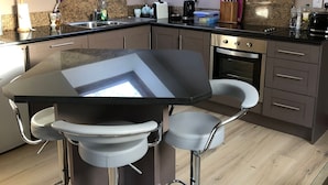 Eine moderne Küche mit Oberlichter, dunklen Arbeitsplatten und Barhocker.