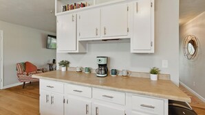 Una cocina con armarios blancos, una encimera y una cafetera.
