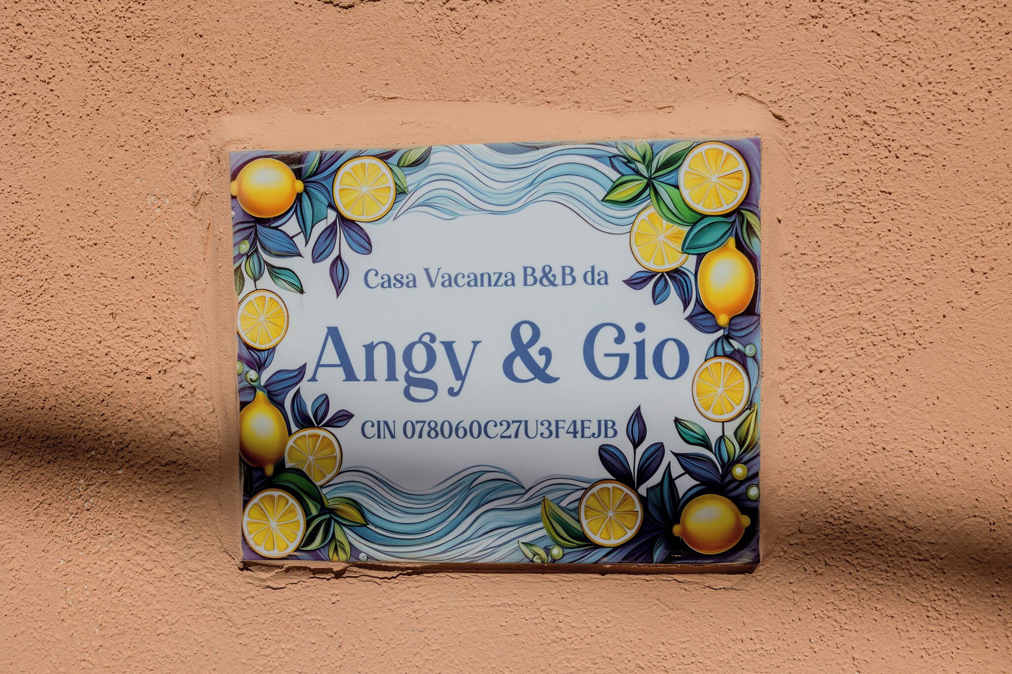Une mosaïque en céramique aux couleurs vives, ornée de motifs de citrons et de feuilles, et portant l'inscription « Casa Vacanza B&B da Angy & Gio » ainsi qu'un numéro CIN.