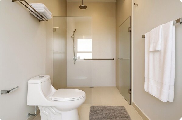 A modern bathroom with a toilet, shower, and glass door.
