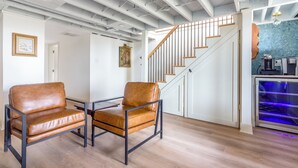 A modern interior with a staircase, two leather chairs, and a coffee machine. - Lakefront Cottage with Hot Tub & Beach Access (Fennville)
