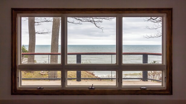 A room with a large window overlooking a beach and ocean. - Lakefront Cottage with Hot Tub & Beach Access (Fennville)