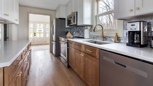 A modern kitchen with white cabinets, stainless steel appliances, and a large window. - Lakefront Cottage with Hot Tub & Beach Access (Fennville)