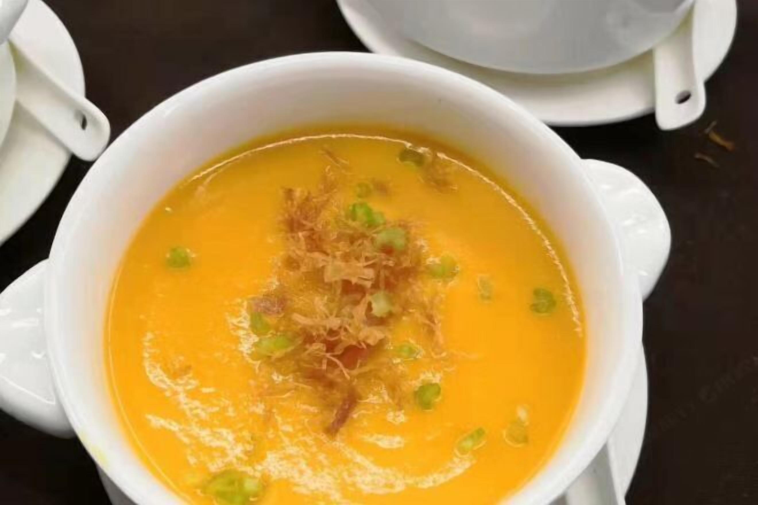A bowl of soup with a garnish, served in a white bowl on a table.