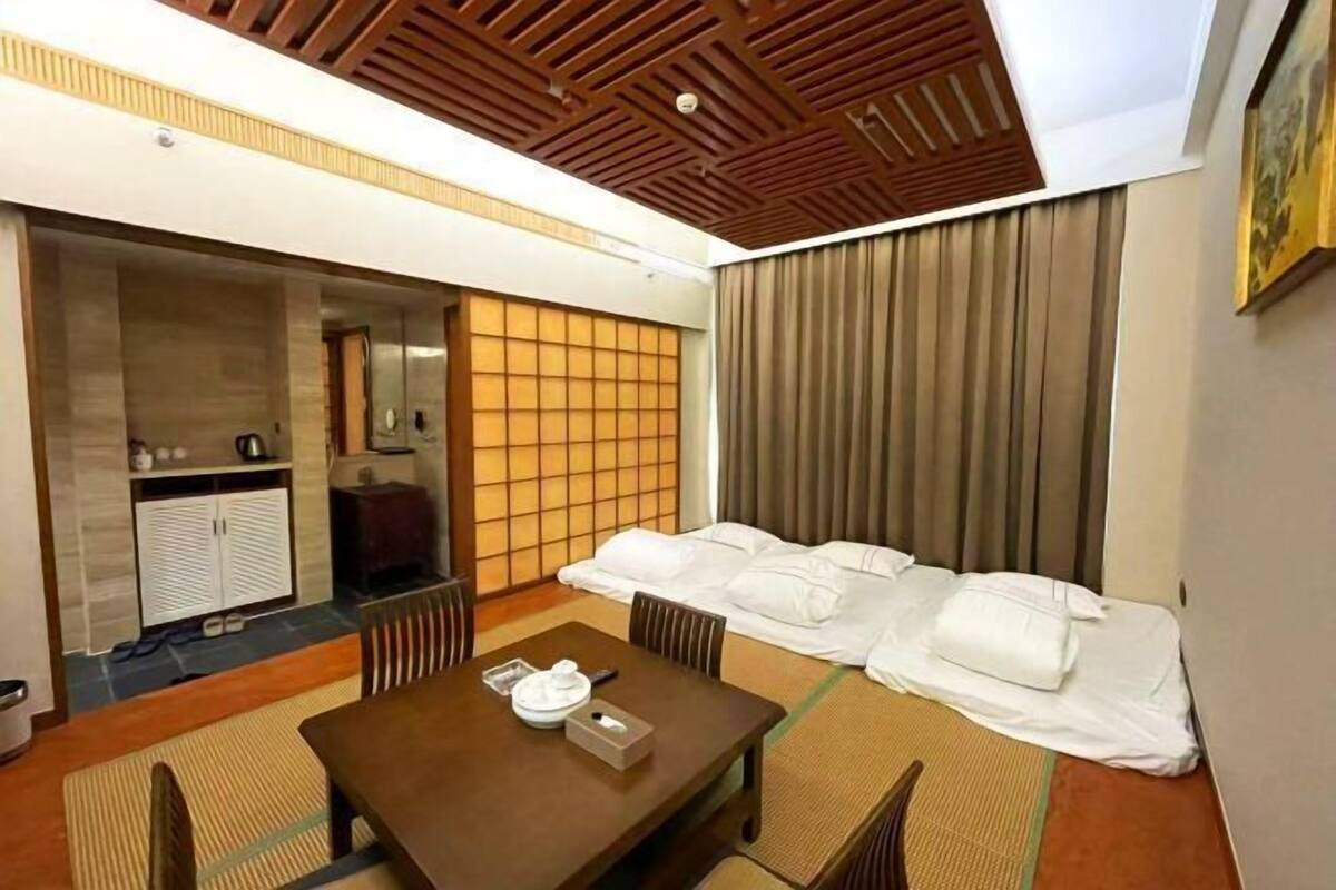Quarto de hotel com chão de tatame em estilo japonês tradicional, uma mesa de jantar de madeira e uma cama futon.