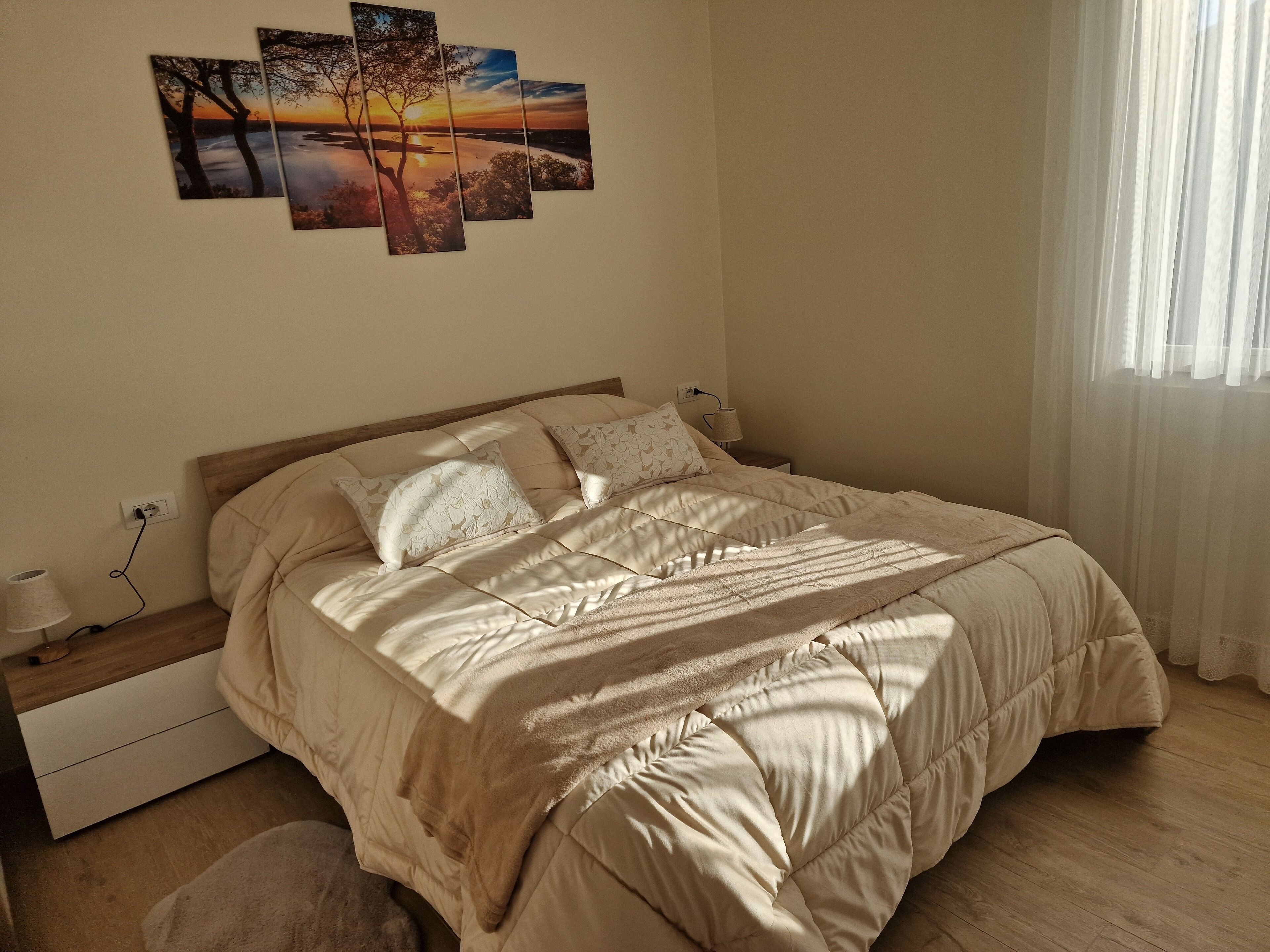 A bedroom with a bed, bedside tables, a lamp, and a wall-mounted artwork.