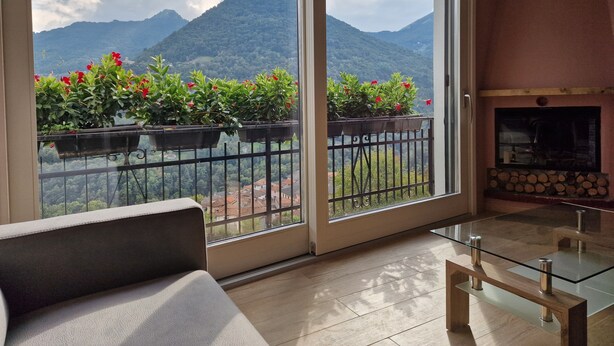 A balcony with a view of mountains, a sofa, and a glass table. - 3-bedroom apartment in gorgeous Dizzasco with WiFi (Dizzasco)