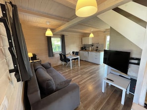 Un interior moderno con sofá, mesa de comedor, cocina y televisor.