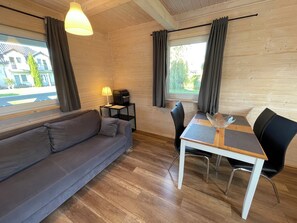 Una habitación acogedora con sofá, una mesa con sillas, una lámpara y televisión.