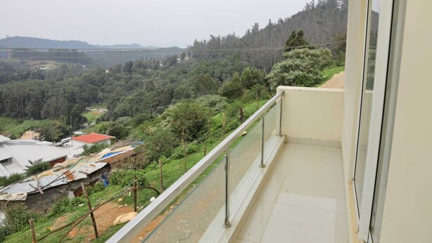 Un balcón con vistas a un paisaje montañoso, que incluye árboles y edificios.