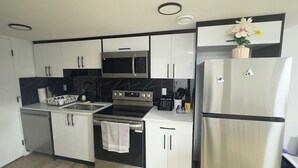 A modern kitchen with stainless steel appliances, white cabinetry, and a marble backsplash.