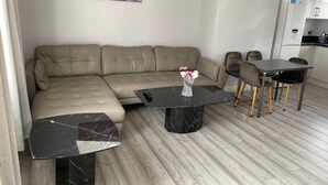 A modern living room with a sectional sofa, a marble coffee table, and a dining area with a small table and chairs. - 3 Bedroom House- Loughborough-sleeps 5-freeparking (Loughborough)
