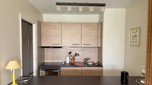 A modern kitchen with wooden cabinets, a built-in oven, and a coffee machine.
