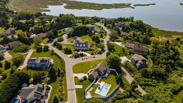 Vista aérea de uma área residencial com casas, uma grande propriedade e um lago.