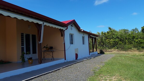 A two-story building with a red roof, a balcony, and a gravel driveway.