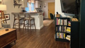 A modern kitchen with a central island, bar stools, a dining table, and a bookshelf with books. - Charming 2-bedroom cottage 10 min to downtown - King bed - Fireplace (Nashville)