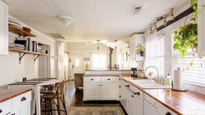 A kitchen with white cabinets, a wooden countertop, and a dining area with a table and chairs. - Charming 2-bedroom cottage 10 min to downtown - King bed - Fireplace (Nashville)