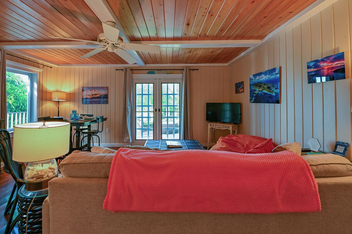 A cozy room with a bed, a desk, and a TV. There is a window and a door leading outside.