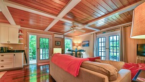Un salon spacieux avec un canapé beige, un plaid rouge et un ventilateur de plafond.