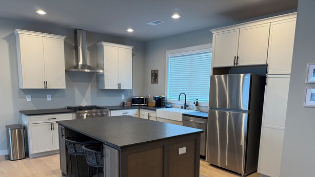 A modern kitchen with white cabinets, stainless steel appliances, and a central island with bar stools.