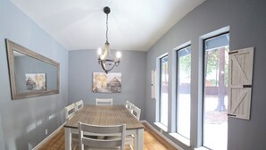 A dining room with a wooden table and chairs, a chandelier, and large windows with a view of the outdoors. - Entire home just 14 miles from Lassen Volcanic National Park (Shingletown)
