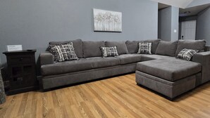 A grey sectional sofa with patterned cushions, a small dark wooden side table, and a framed artwork on the wall. - Entire home just 14 miles from Lassen Volcanic National Park (Shingletown)