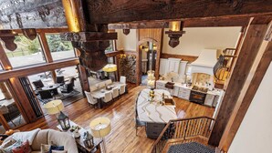 Amplia sala de estar con una gran mesa de comedor, diversas opciones de asiento y una cocina con armarios blancos y detalles de madera.