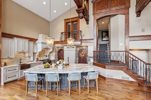 Enjoy cooking in this stylish kitchen with a large island, high ceilings, and a central chandelier.